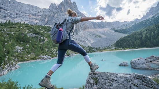 Frau springt über Steine in Berglandschaft