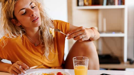 Nahaufnahme einer jungen Frau, die zu Hause frühstückt
