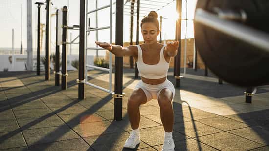 Eine Frau macht draußen Squats in der Sonne