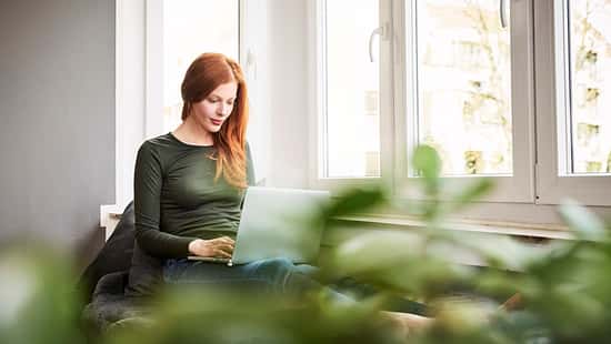 Eine rothaarige Frau arbeitet am Laptop