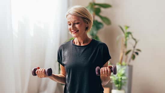 Eine Frau mittleren Alters macht Bizep-Curls mit kleinen Hanteln