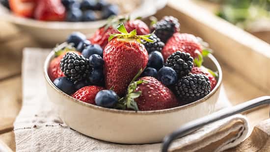Ripe sweet different berries in a bowl on kitchen table.