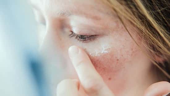 Frau trägt Creme im Gesicht auf