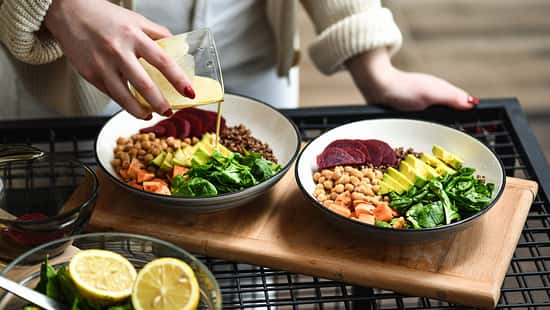 Frau bereitet einen leckeren Salat mit Kichererbsen zu und Dressing hinzu