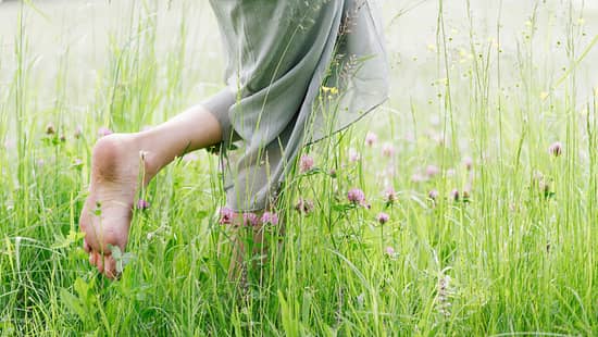 Eine Frau läuft barfuß durch hohes Gras.