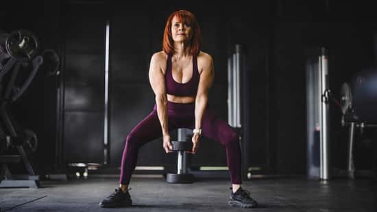 Eine trainierte Frau macht Kniebeugen mit einer Kettlebell