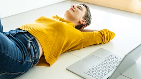 Woman relaxing on the floor with a laptop in a bright office space