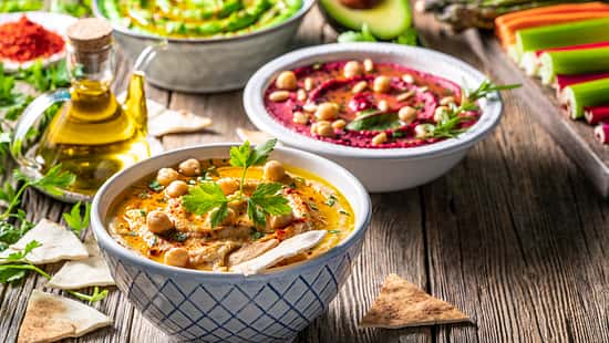 Hummus Three bowl of chickpeas, avocado and beetroot vegetables for dip on rustic wooden table