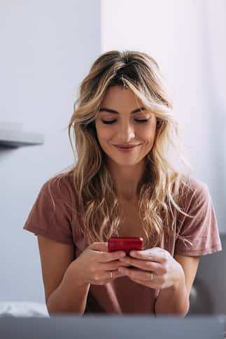 A Blonde Woman Texting And Smiling
