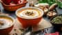 Eine Kürbissuppe in einer Schale auf einem Brett Eine Kürbissuppe in einer Schale auf einem Brett