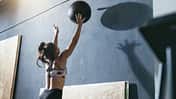 Frau wirft einen Medizinball an die Wand