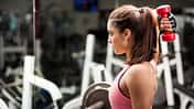 Frau im Gym macht Trizeps-Übung mit Hantel
