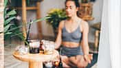junge Frau praktiziert Yoga bei Kerzenlicht in gemütlicher Atmosphäre