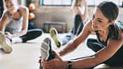 Drei Frauen dehnen sich in einem Fitnessstudio.