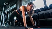Frau macht eine Stützübung am Boden im Gym und schwitzt