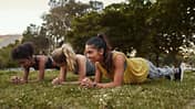 Drei Frauen machen Planks im Park.