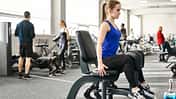 Frau sitzt an einer Adduktoren-Maschine im Gym.
