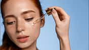 Beautiful,Young,Woman,Apply,Moisturizing,Facial,Serum,Isolated,On,Blue