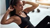 junge trainierte Frau führt eine Fitnessübung durch und schwitzt dabei
