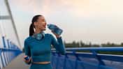 Fit,European,Woman,Relaxing,And,Drinking,Water,On,Seaside,Promenade