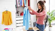 Young,Woman,Folding,Her,Clothes,And,Packing,Them,In,A