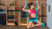 Eine junge, trainierte Frau treibt Sport in einem Aerial Yoga Tuch