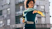 Junge Frau läuft auf der Straße und überprüft ihre Smart Watch