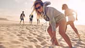 Young woman running race with friends at the beach