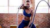 Sportliche junge Frau trainiert intensiv CrossFit mit Seil