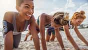 Three young women doing push-ups on the beach