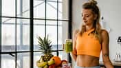 Trainierte Frau mit Smoothie und Obst