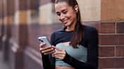 Frau mit Kopfhörern schaut auf ihr Handy