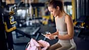 Frau in Sportkleidung schaut auf ihr Handy