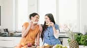 Two happy women in kitchen preparing fruit