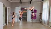 Poledance-Instruktorin coacht zwei junge Frauen in einem Tanzstudio