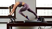 Eine Frau macht Pilates-Übungen an einer Reformer-Pilates-Maschine