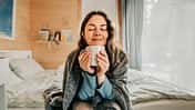 Serene woman savoring the aroma of coffee in her cozy bedroom