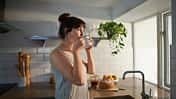 Woman drinking from mug in zero waste kitchen.
