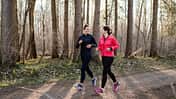 Zwei Frauen gehen in Laufkleidung im Wald und unterhalten sich Zwei Frauen gehen in Laufkleidung im Wald und unterhalten sich