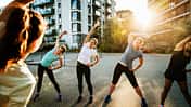 Eine Sportgruppe von Frauen wärmt sich im der Stadt vor dem Laufen gehen auf