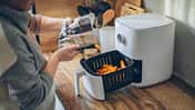 Eine Frau bereitet Kartoffeln im Airfryer zu Eine Frau bereitet Kartoffeln im Airfryer zu