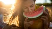 Eine Frau beißt im Sonnenlicht in eine Wassermelone
