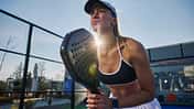 Eine sportliche Frau spielt draußen Padel