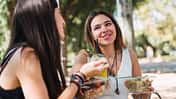 Zwei junge Frauen sitzen im Park und essen Salat