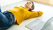 Woman relaxing on the floor with a laptop in a bright office space