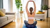 Eine Frau von hinten, wie sie auf einer Yogamatte Übungen für den Rücken praktiziert
